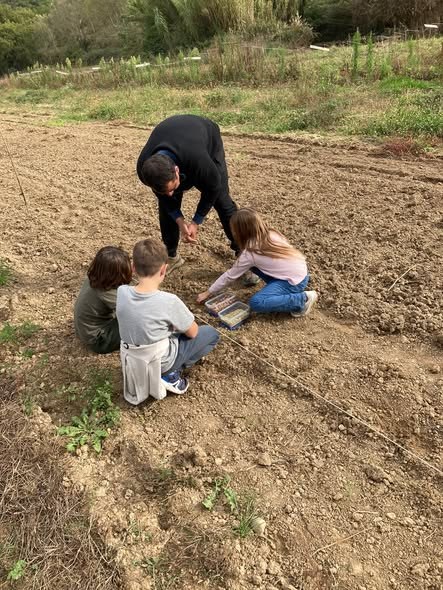 Anthony et des enfants au semis dans un champ de la ferme